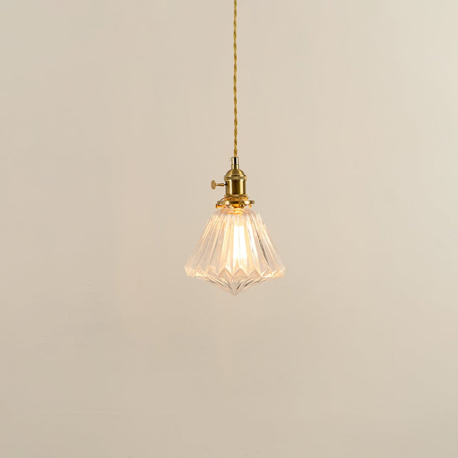 Clear glass pendant light with brass holder glowing softly on white background for elegant living room lighting.