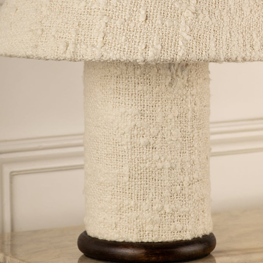 Textured fabric wrapped table lamp base with dark wood trim showcasing handcrafted detail and natural material appeal.