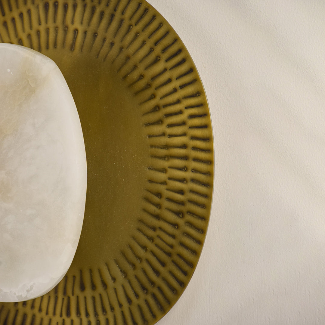 Closeup of textured gold metal and marble wall light for luxury bedroom and modern decor styling spaces.

