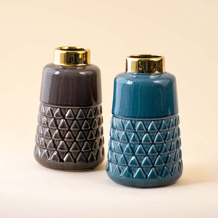 Two ceramic vases one in brown and one in teal displayed together on a white background showcasing their textured geometric bases and shiny golden tops as a stylish set.