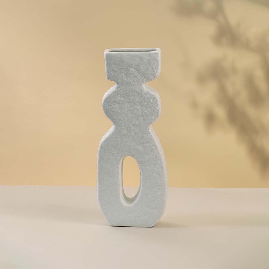 Minimalist white sculptural ceramic vase showcasing a tall elongated design with smooth matte finish against white background.