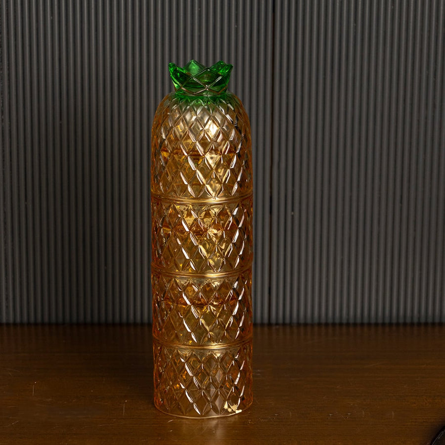 Amber pineapple shape glass tumblers with diamond pattern and green lid creating elegant look for parties and dining.