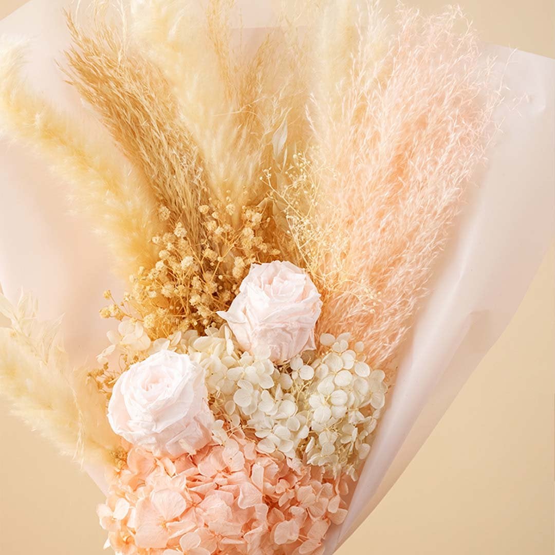 Closeup of pastel dried bouquet with preserved pampas grass light pink hydrangea infinity rose and delicate babysbreath creating a rustic floral gift.