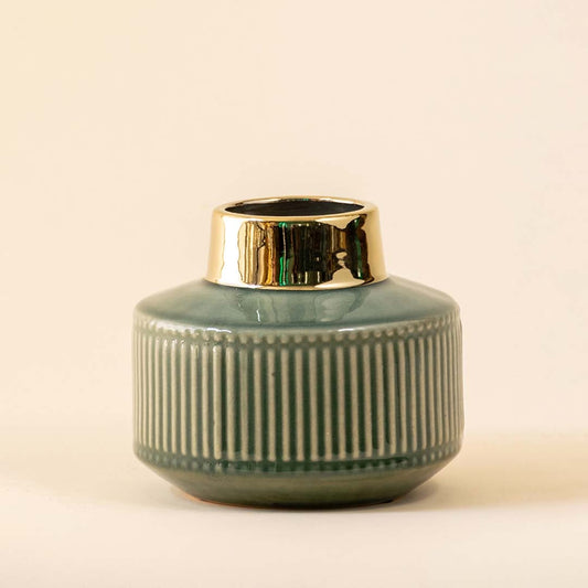 Elegant green ceramic vase with a ribbed texture and shiny gold detailing displayed on a white background showcasing its modern rounded shape.