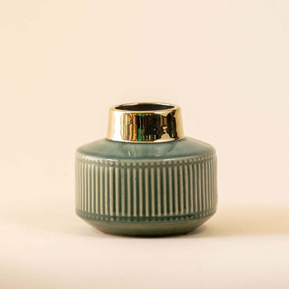 Green ribbed ceramic decorative jar with gold rim displayed on white background adding elegant accent for shelf or tabletop decor.