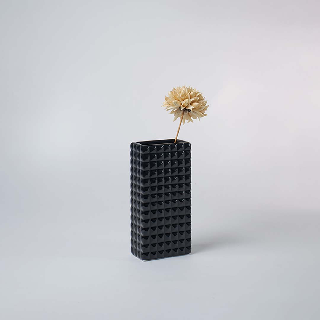 Black textured vase displayed on a minimal console table with dried flower decor for elegant home styling.