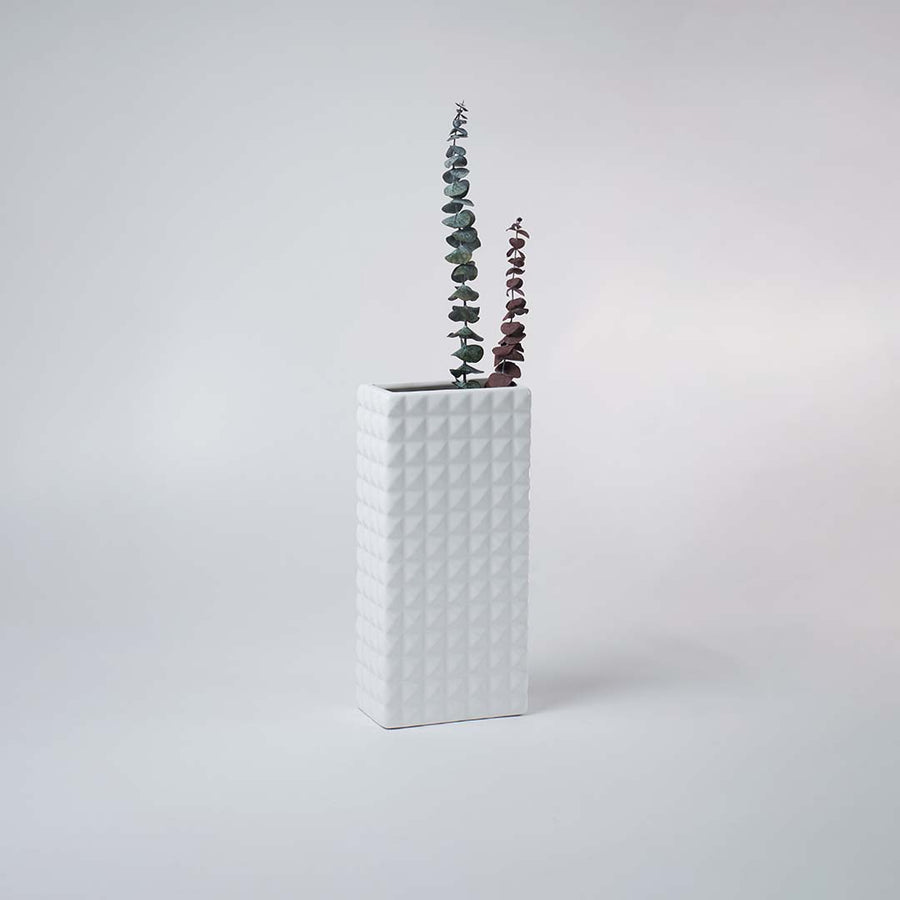 Minimal white ceramic vase with geometric texture placed on a soft background creating a clean contemporary decorative accent.