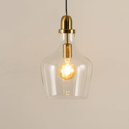 Clear glass and brass metal pendant light with exposed bulb adding warmth to stylish interiors.