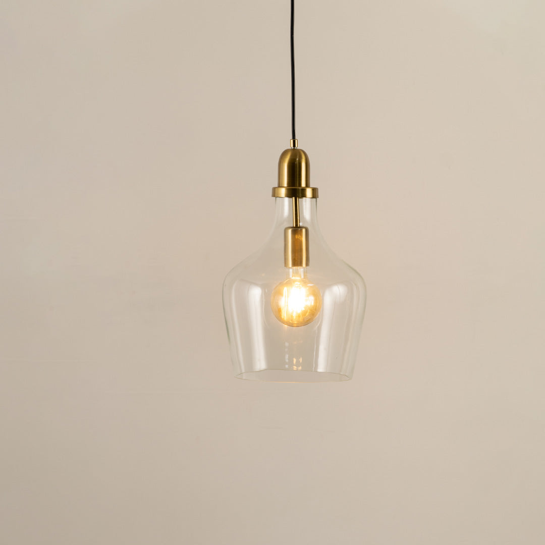 Clear glass and brass metal pendant light with warm glow for elegant contemporary home decor spaces.
