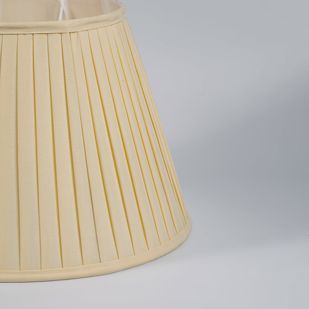Closeup view of cream pleated fabric lampshade showcasing fine texture and handcrafted detailing for elegant interiors.