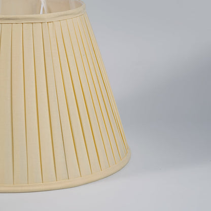 Closeup view of cream pleated fabric lampshade showcasing fine texture and handcrafted detailing for elegant interiors.
