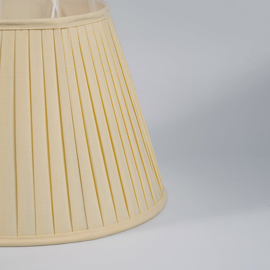 Closeup view of cream pleated fabric lampshade showcasing fine texture and handcrafted detailing for elegant interiors.