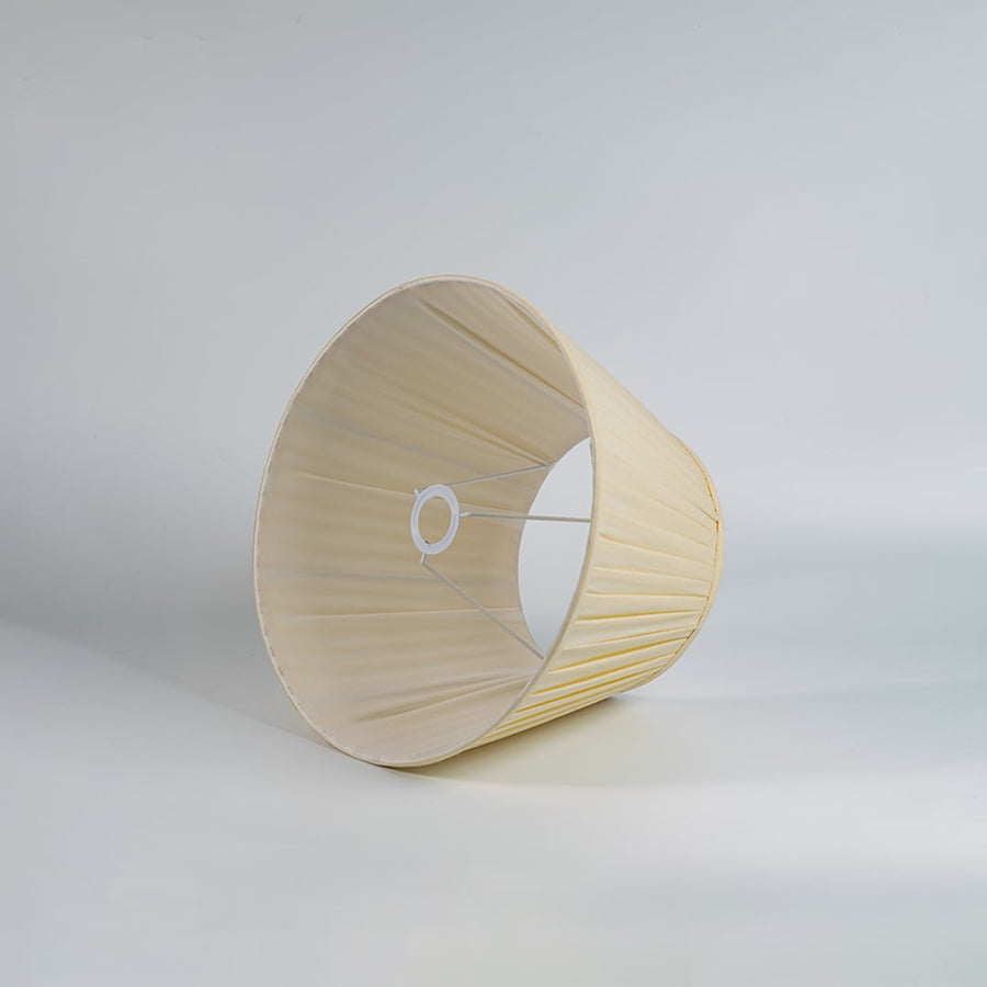 Cream pleated fabric lampshade with tapered silhouette and textured finish designed for table lamps and home decor.