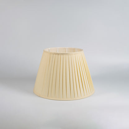 Cream pleated fabric table lamp with textured shade and wooden base designed for bedrooms and living spaces.