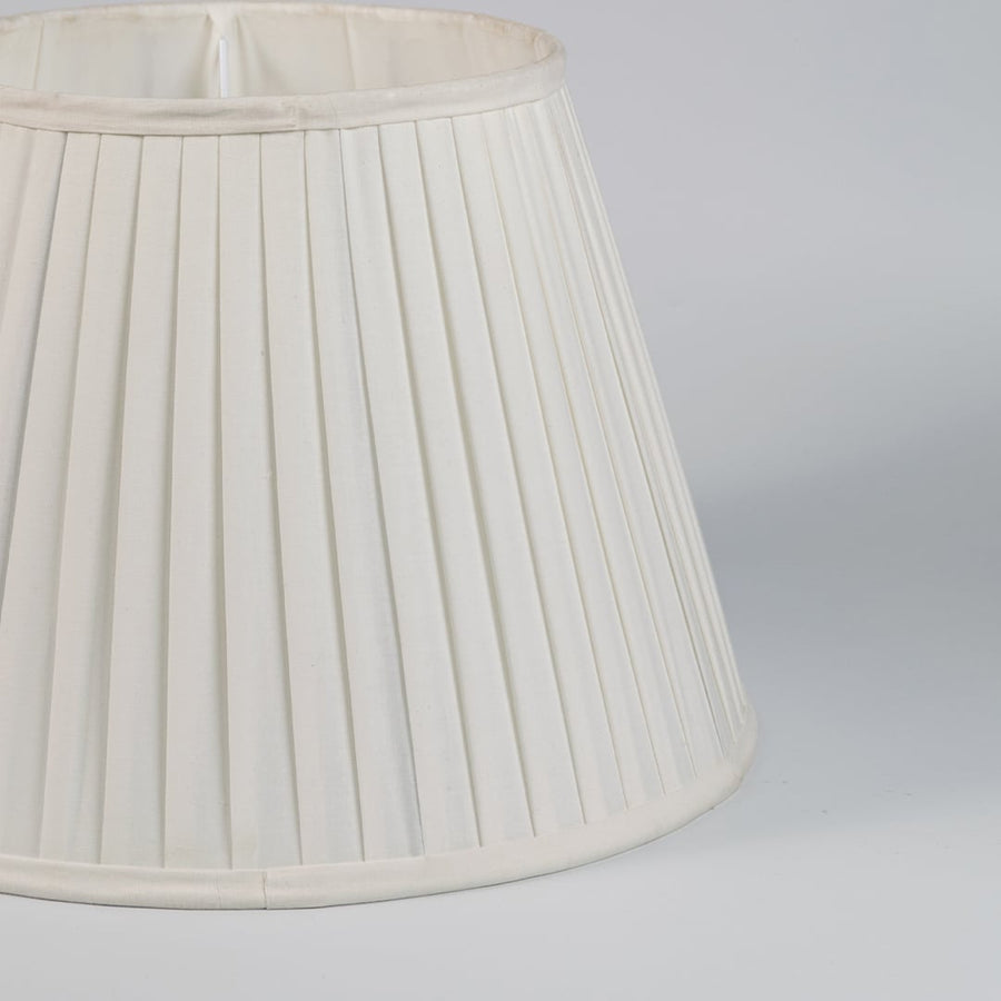 Closeup view of cream pleated fabric lampshade showcasing fine folds and handcrafted texture for refined interiors.