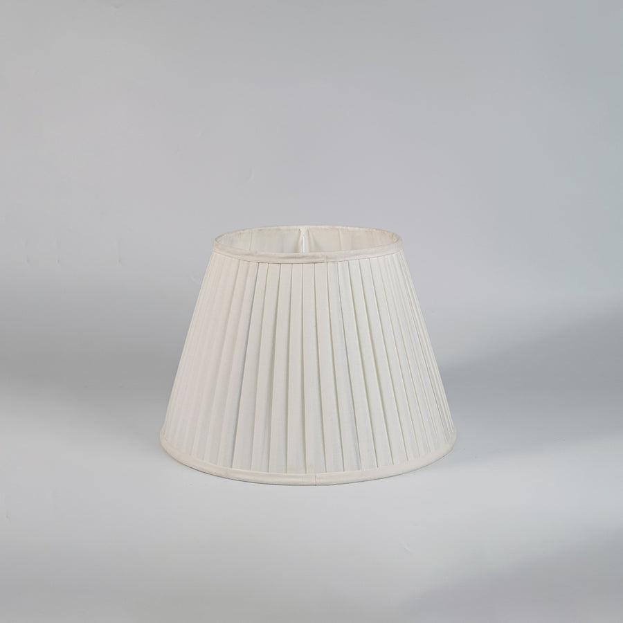 Cream pleated fabric lampshade with tapered silhouette and textured finish designed for elegant table lamp styling.
