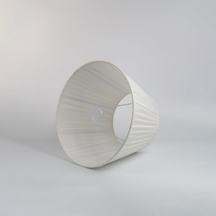 Cream pleated fabric lampshade with tapered silhouette and soft texture designed for elegant table lamp styling.