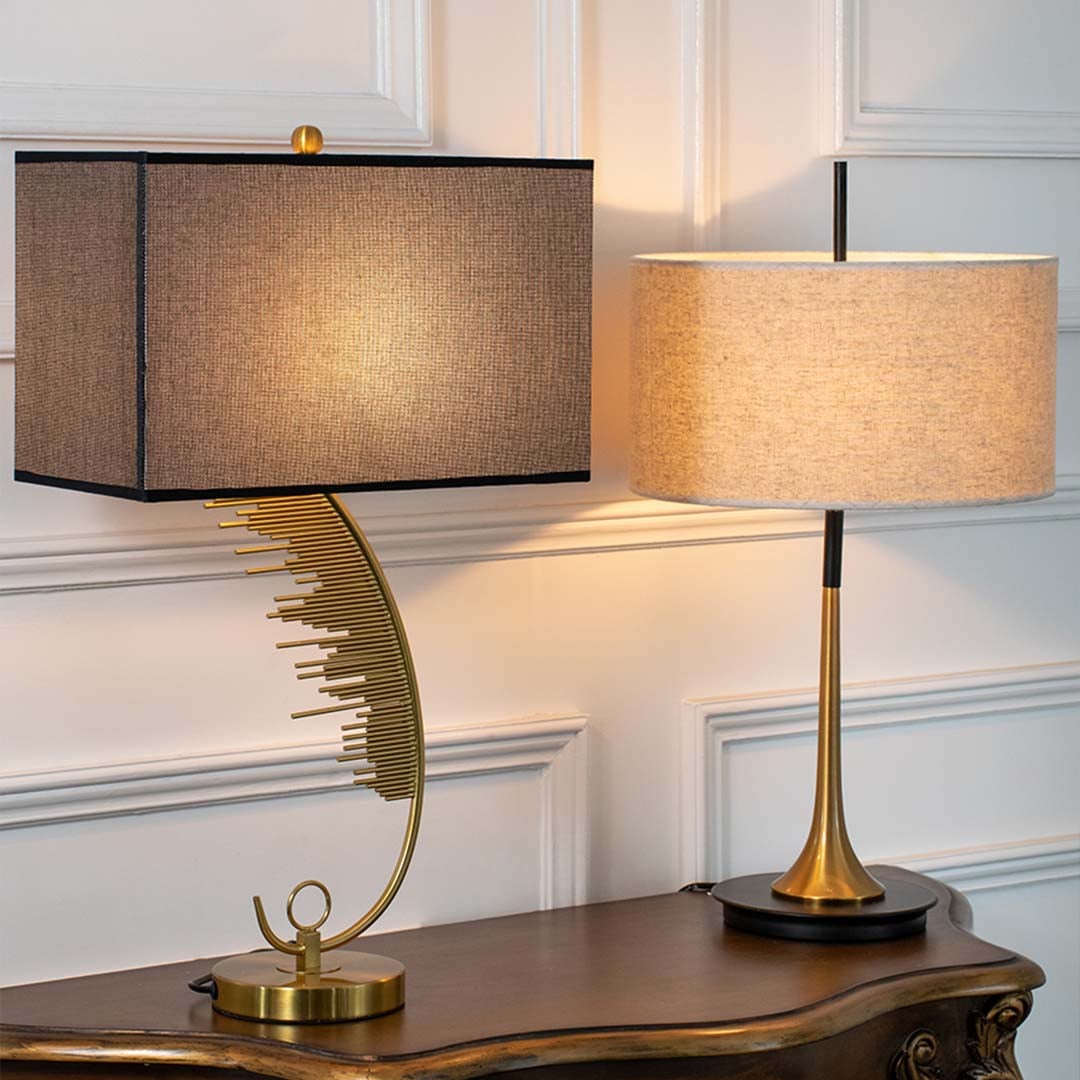Gold curved base table lamps with illuminated black shades displayed together showcasing warm dramatic lighting options for modern home decor.