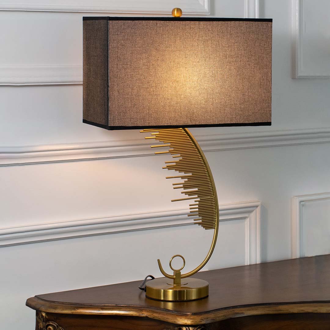 Gold metal table lamp with black fabric shade and leaf design base offering luxury decor and warm ambient lighting.