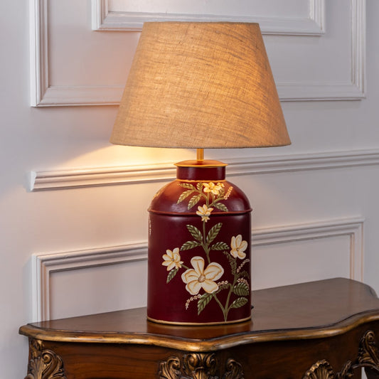 Plumeria red table lamp turned on against white background showing vibrant floral pattern warm glow and lively interior decor tone.