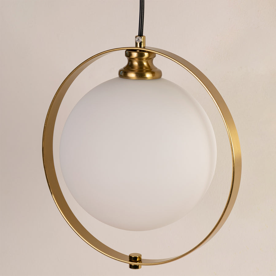 Closeup of gold metal pendant light with circular frame and glass globe on white background ideal for premium interior decor.