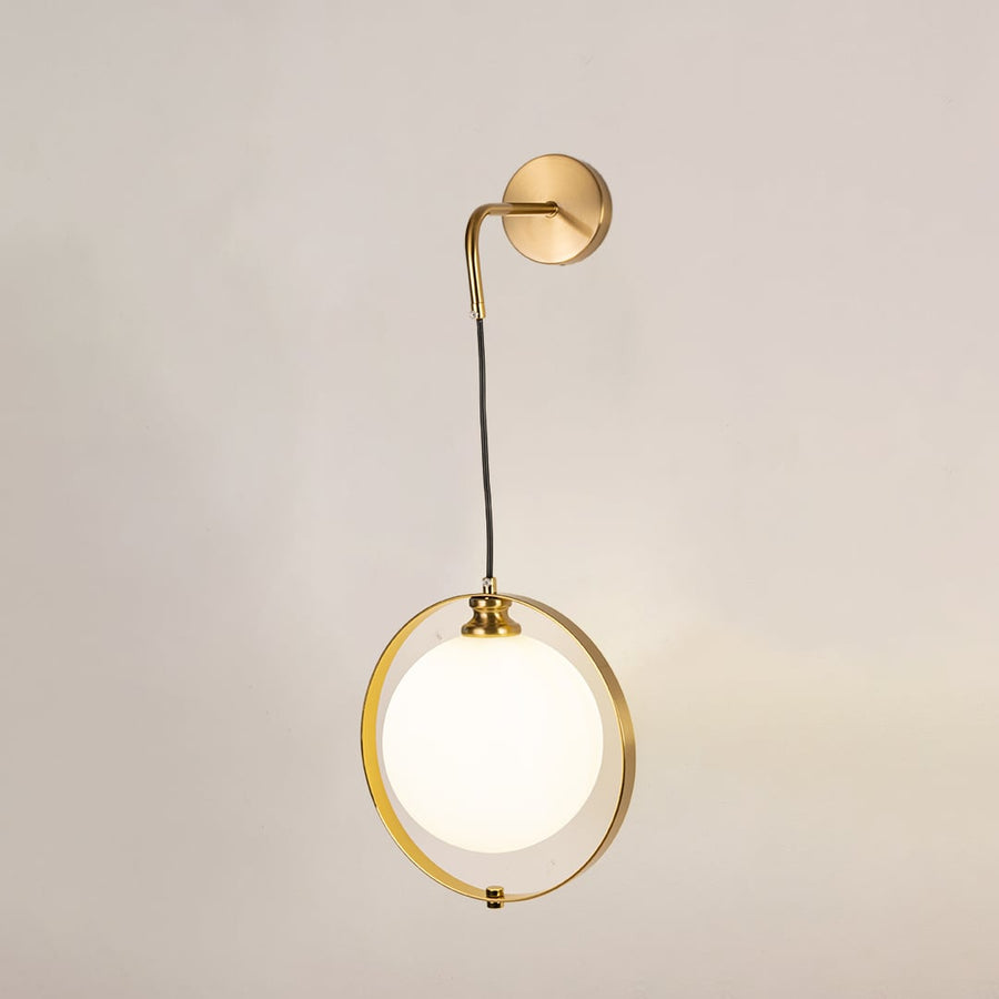 Gold ring wall light with frosted glass globe glowing softly on a clean white background showcasing elegant modern lighting.