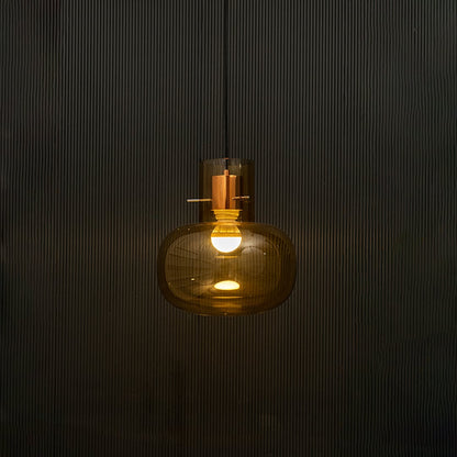 Amber glass ceiling pendant light illuminated beautifully on dark background highlighting elegant reflective texture.