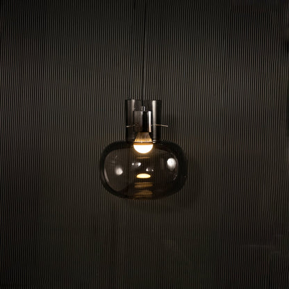 Smoked glass wall light glowing on black background with warm filament bulb creating moody modern accent lighting for interior walls.