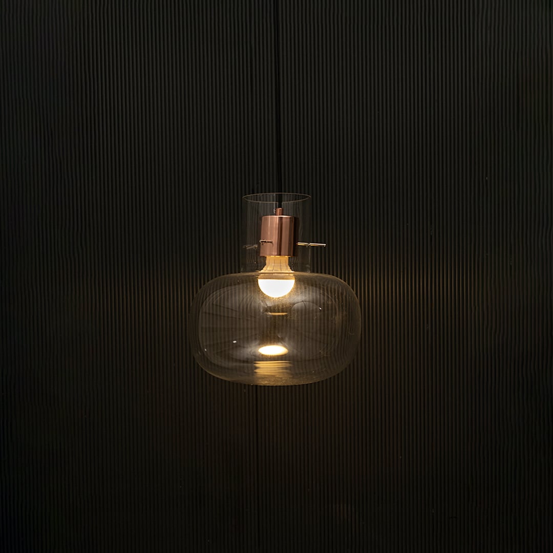 Elegant clear glass pendant light illuminated on dark background showcasing modern luxury ceiling light design.