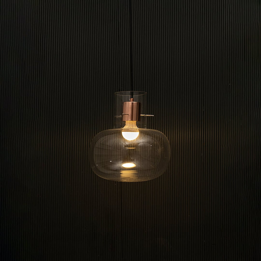 Elegant clear glass pendant light illuminated on dark background showcasing modern luxury ceiling light design.