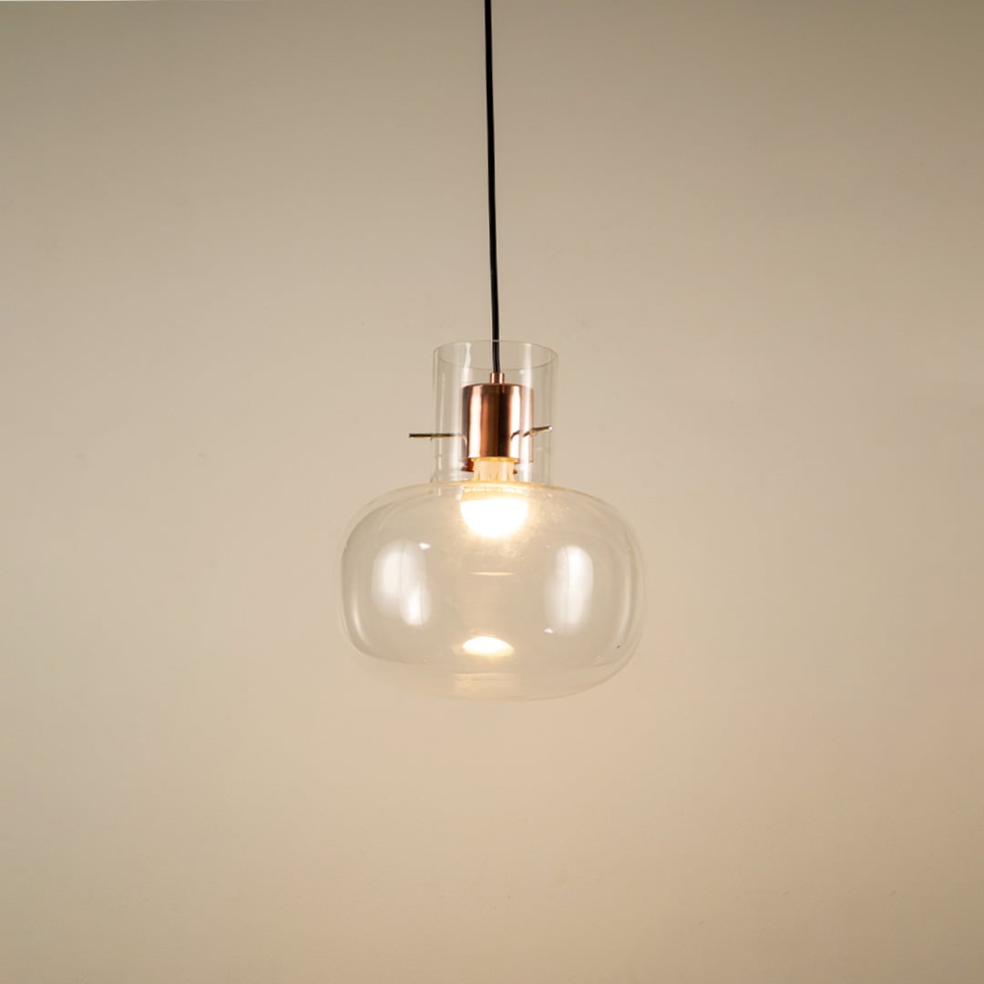 Transparent glass hanging pendant light glowing softly on white background for elegant and modern room ambience.