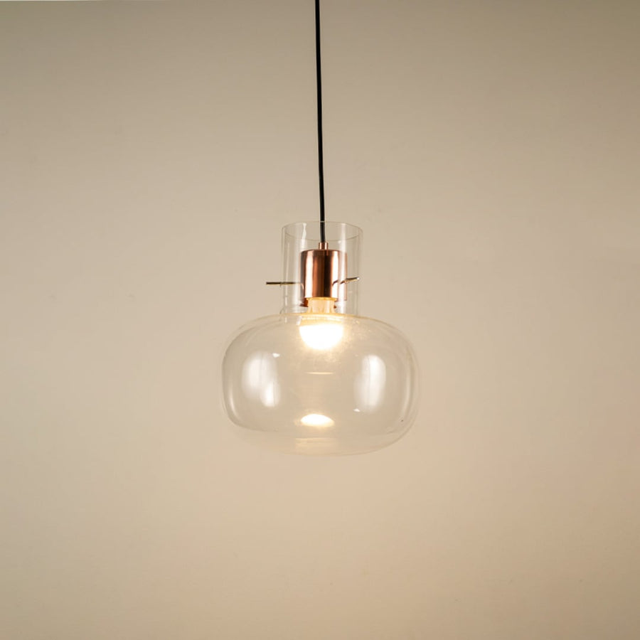Transparent glass hanging pendant light glowing softly on white background for elegant and modern room ambience.