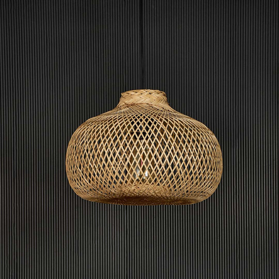 Rattan pendant light displayed off on black background showing intricate handmade weave and organic shape.