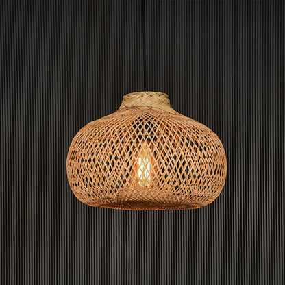 Woven rattan pendant light illuminated against black background highlighting its natural tone and warm glow.