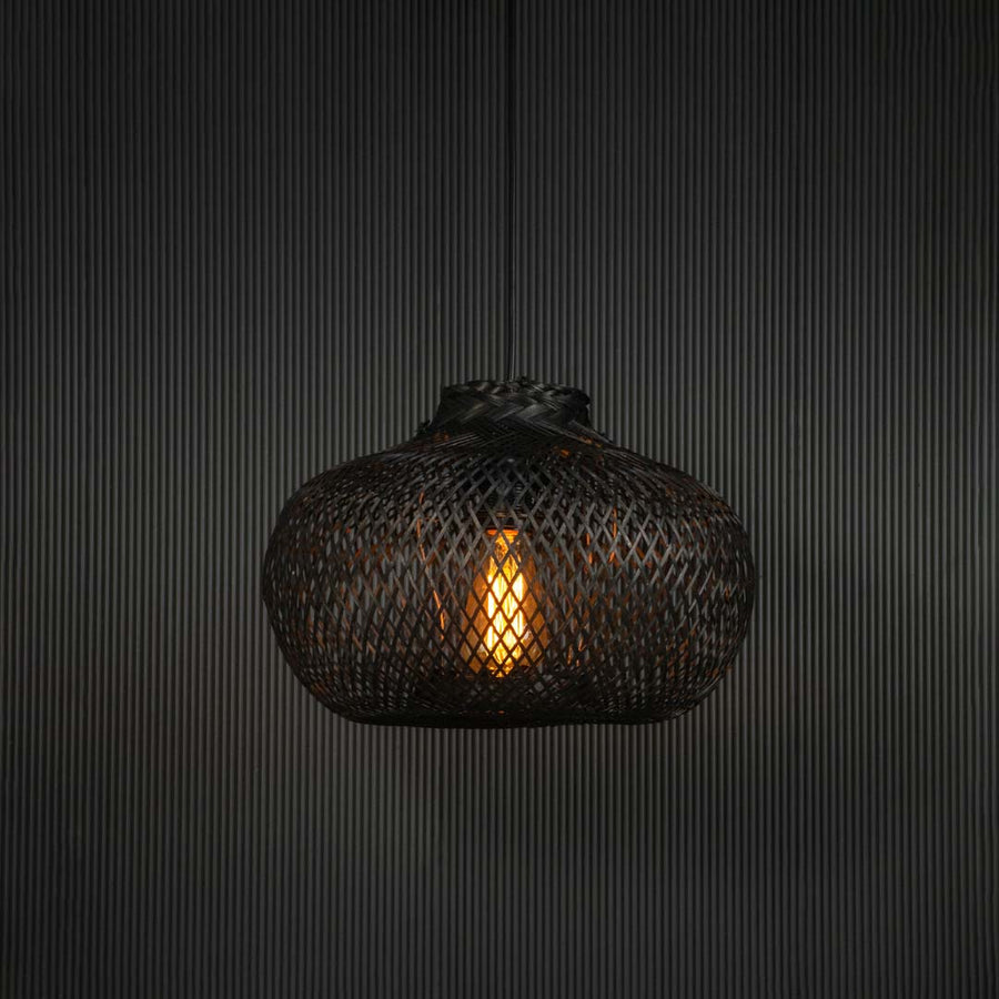 Black rattan pendant light illuminated hanging decor creating warm ambience for living room interiors.