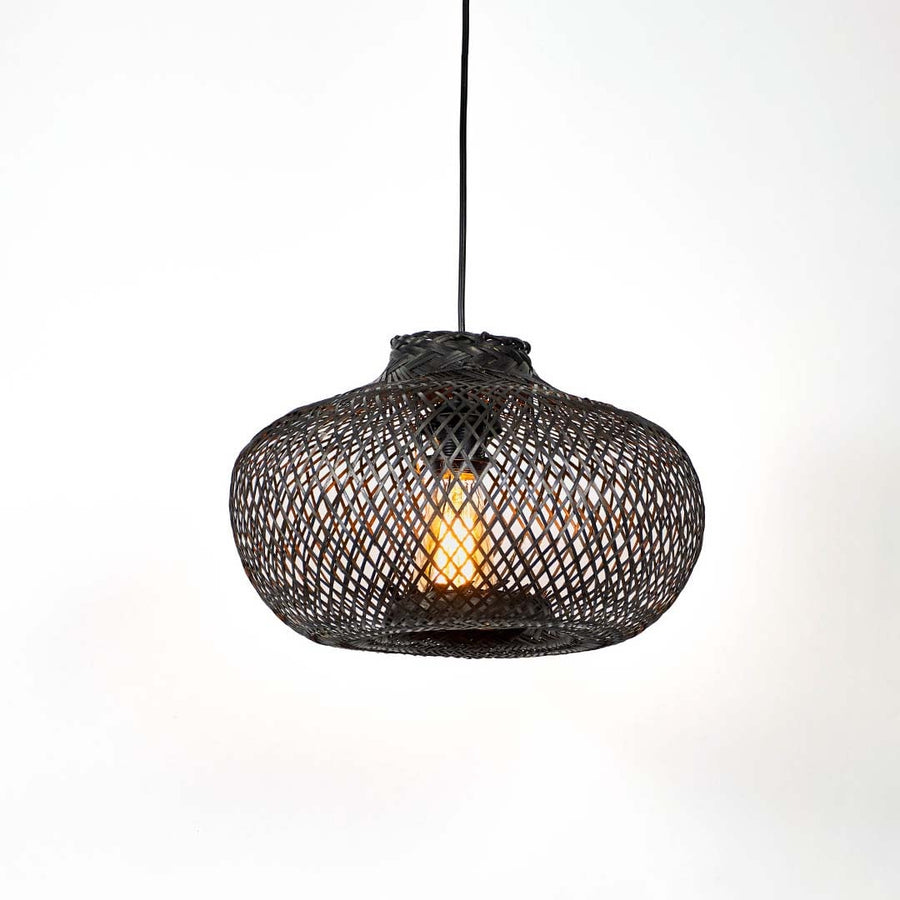 Black woven bamboo pendant light illuminated with warm glow creating elegant modern ambiance.