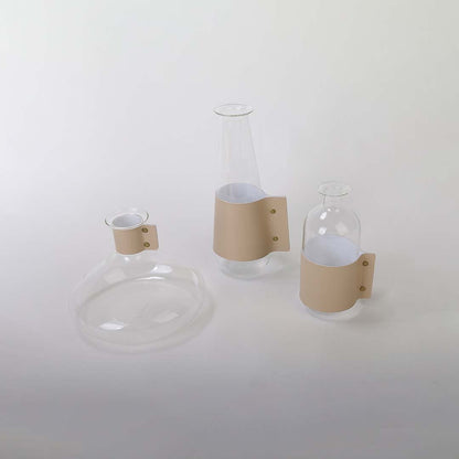 Set of tall transparent glass vases with beige leather wrap grouped image ideal for modern living room and dining table decor.