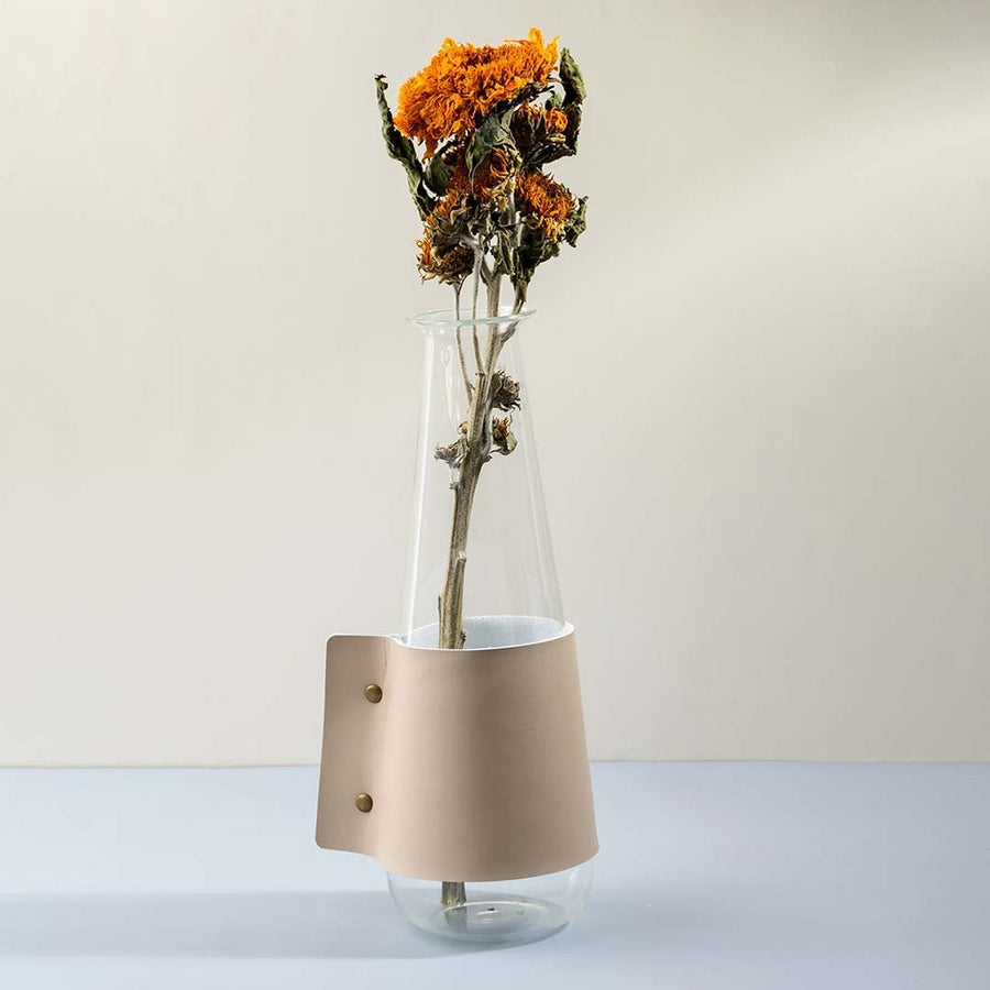 Tall transparent glass vase with beige leather wrap and brass rivets white background image perfect for home table decor.