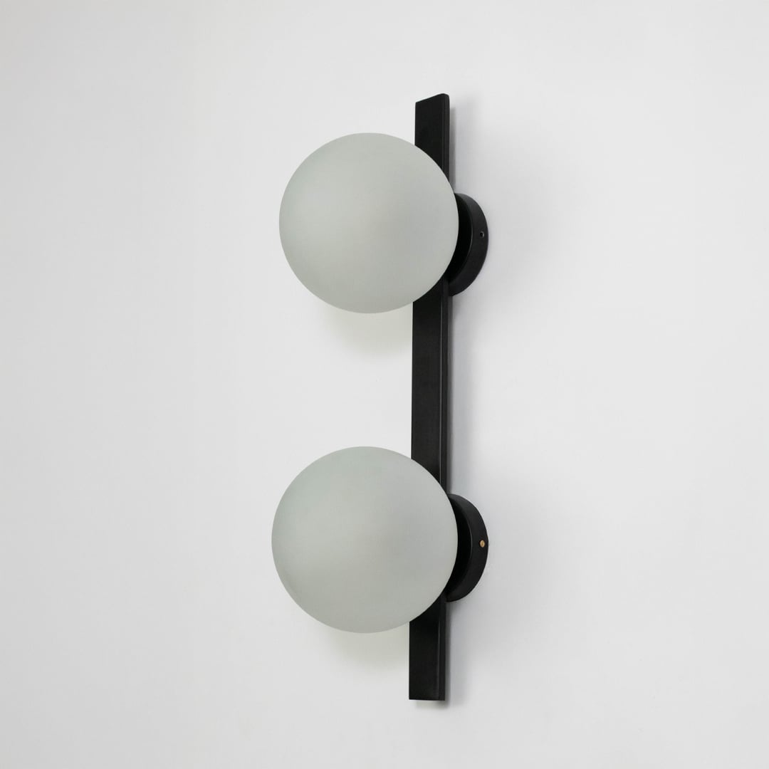 Minimalist wall lamp with frosted oval glass and matte black metal frame displayed on white background.