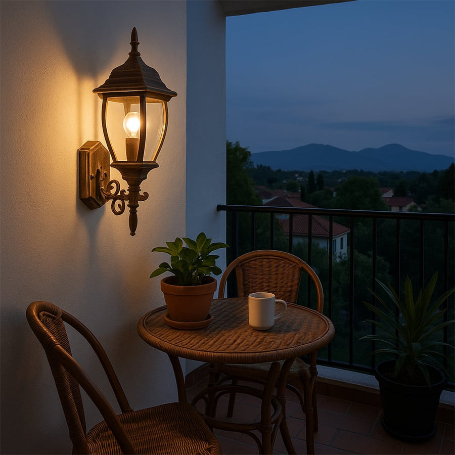 Elegant gold wall lantern showcased in a soft lifestyle setting featuring vintage detailing clear glass panels and a warm glowing bulb.