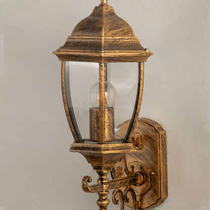 Close view of the gold vintage wall lantern showing its carved detailing clear glass body and warm bulb for a classic decorative look.