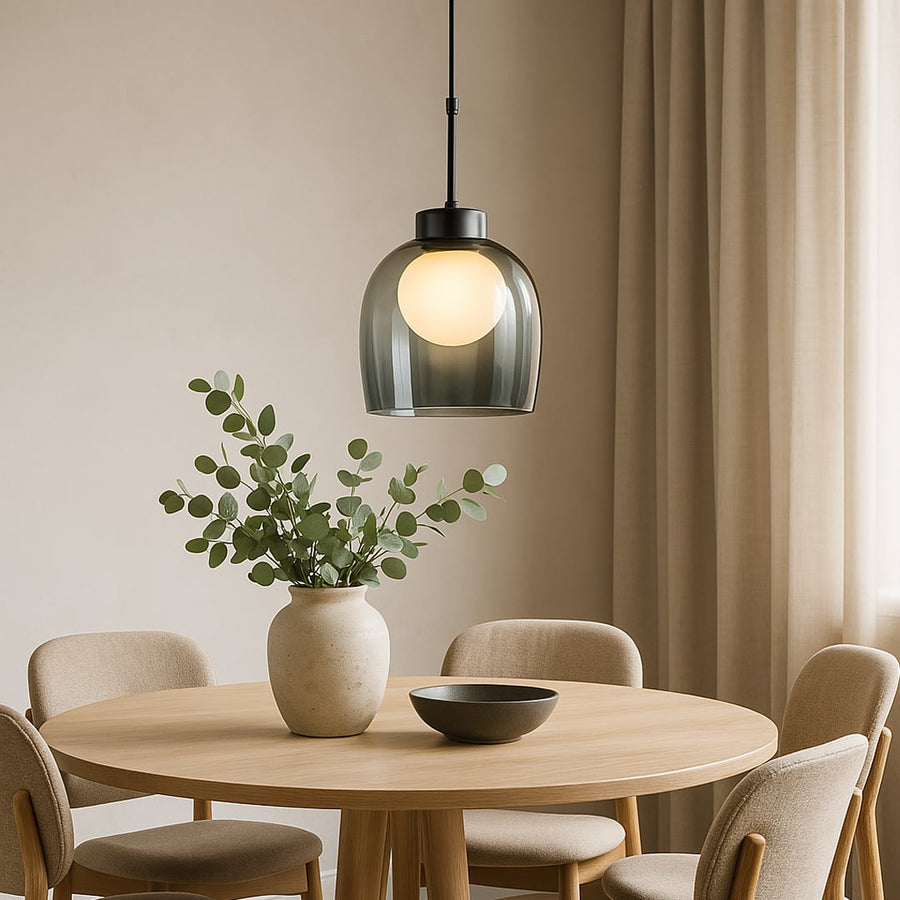 Pendant light with smokey glass dome shade illuminating dining room with round wooden table and modern chairs