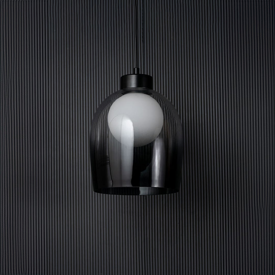Smokey glass dome pendant light bulb off on black background with elegant cylindrical shade and modern fitting.