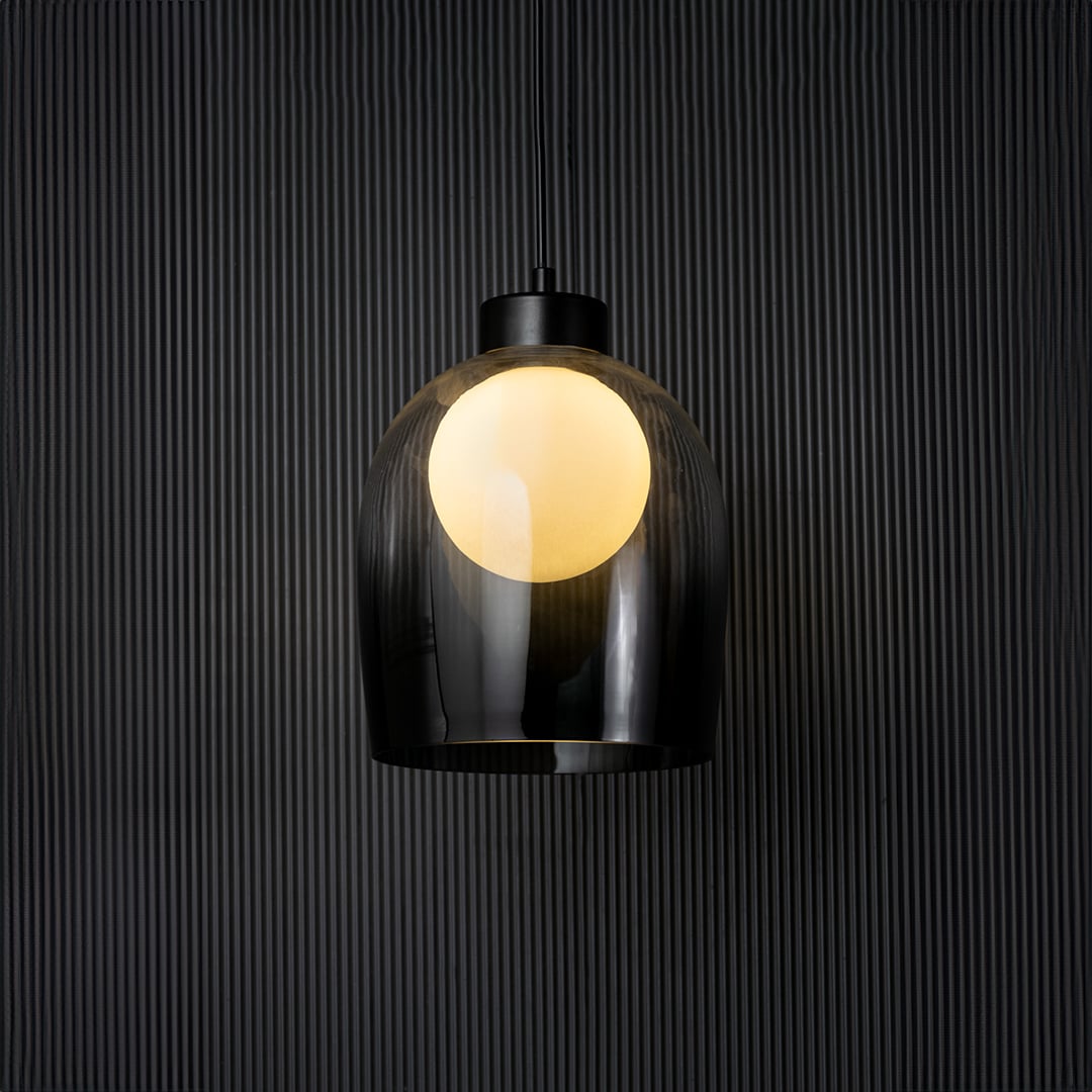 Smokey glass pendant light glowing on black background with elegant dome design and modern style fitting decor.