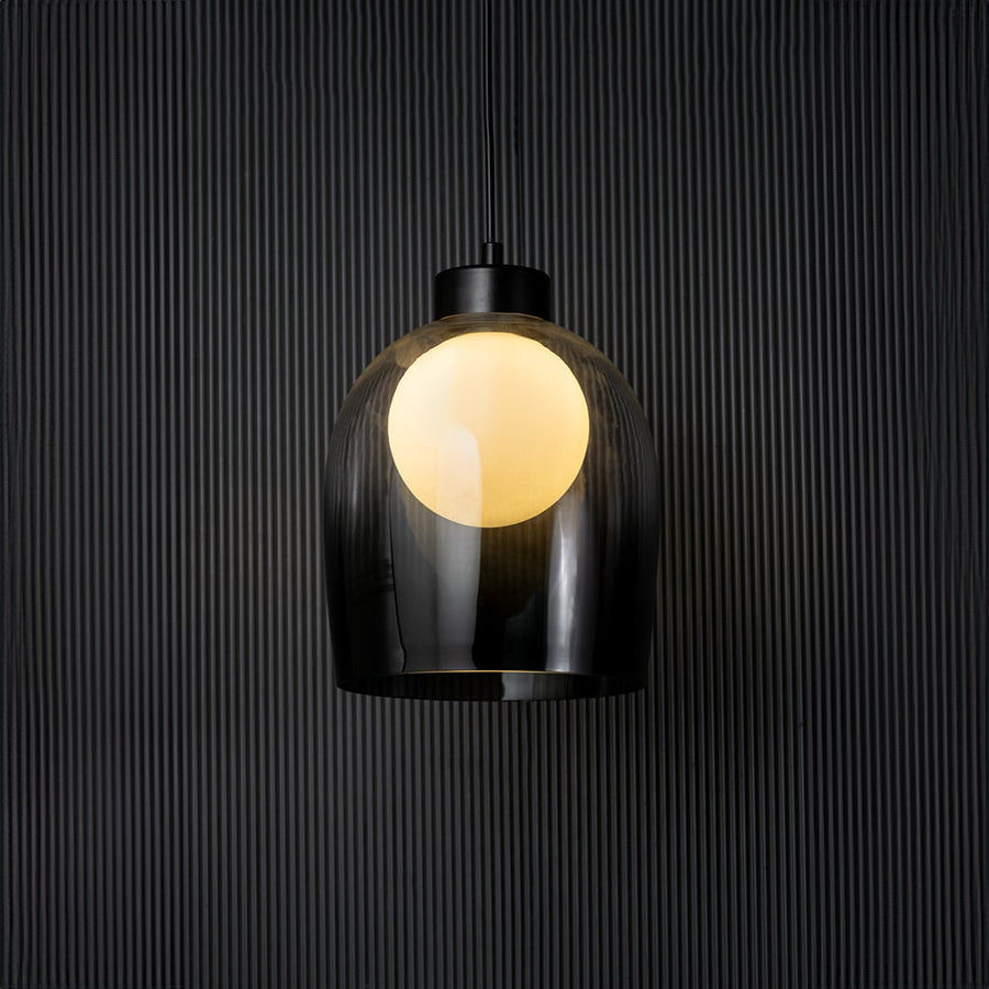 Smokey glass pendant light glowing on black background with elegant dome design and modern style fitting decor.