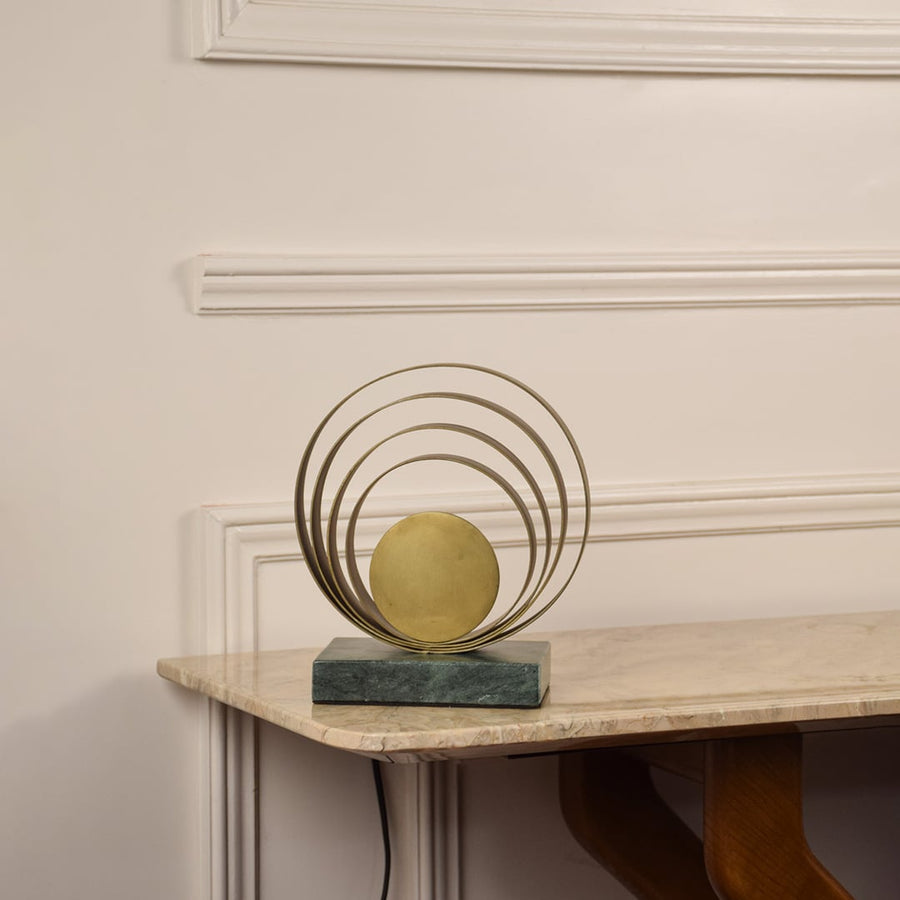 Golden ring lamp unlit on white background featuring layered rings and marble base enhancing modern and minimalist interior aesthetics.