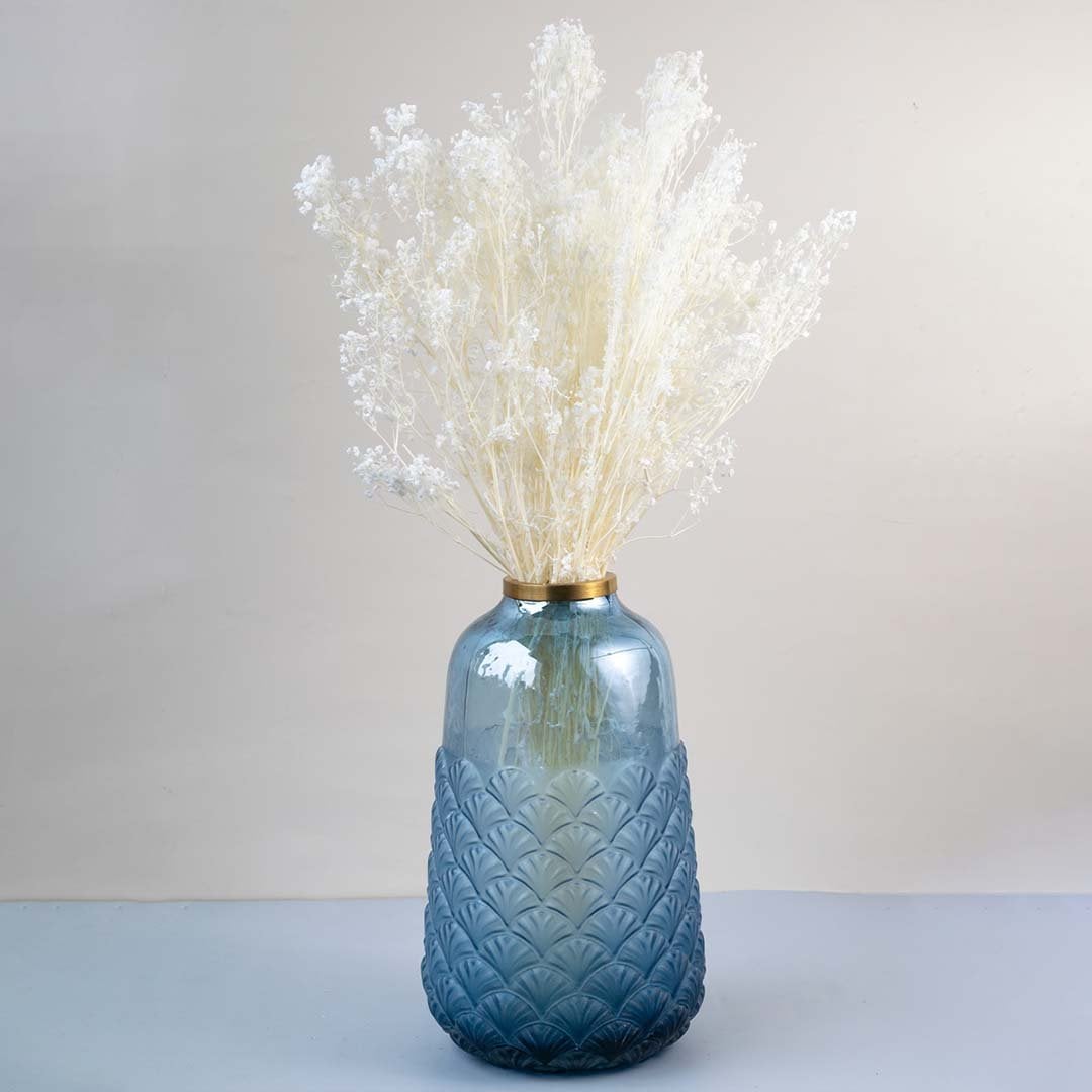 White dried gypsophila bouquet preserved flowers styled in blue glass vase lifestyle decor on table background.
