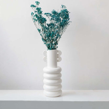 Vibrant turquoise dried gypsophila flowers styled in modern white ceramic vase on white background lifestyle decor.