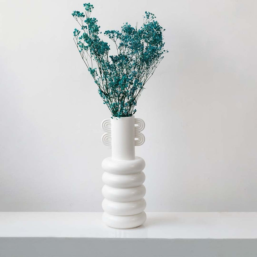 Vibrant turquoise dried gypsophila flowers styled in modern white ceramic vase on white background lifestyle decor.