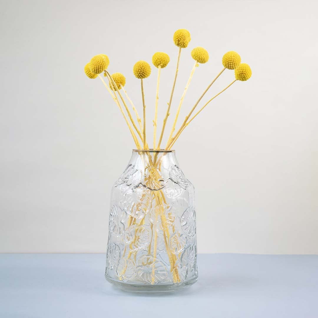Clear glass vase with embossed design styled with yellow dried flower stems modern home decor accent for table.